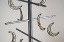 Decorative moon-shaped ornaments hanging from a stand against a neutral background