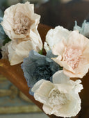 Handmade and hand-dyed crepe paper flowers in solid colors. Bouquets of paper flower Christmas ornaments in blue, white, and pale pink