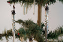 Decorative silver tree ornaments hanging on a Christmas tree.